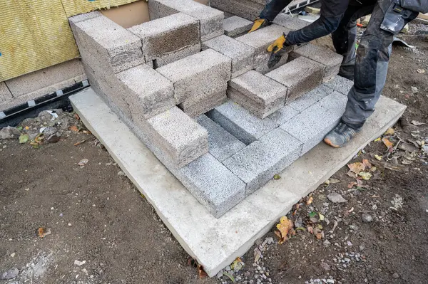 Worker building steps to entrance with light weight cinder blocks Kumla Sweden October 18 2023
