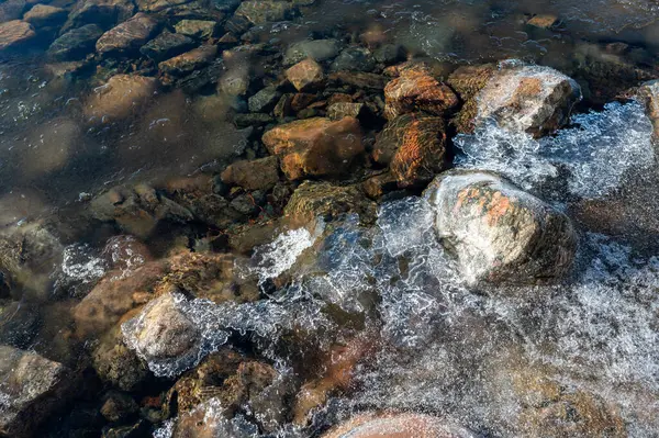 Göl taşlı, berrak su ve buzlu Motala İsveç 9 Şubat 2024