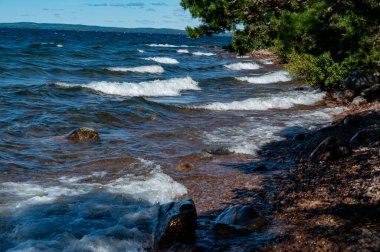 Su, 11 Ağustos 2024 'te Vattern Motala gölündeki kayaların üzerinden taşar.