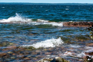 Su, 11 Ağustos 2024 'te Vattern Motala gölündeki kayaların üzerinden taşar.
