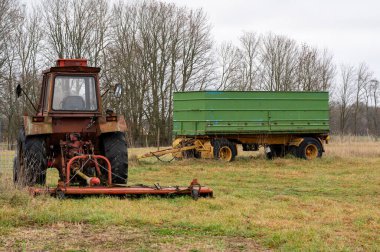9 Kasım 2024 'te çimlerin üzerinde duran eski traktör ve römork.