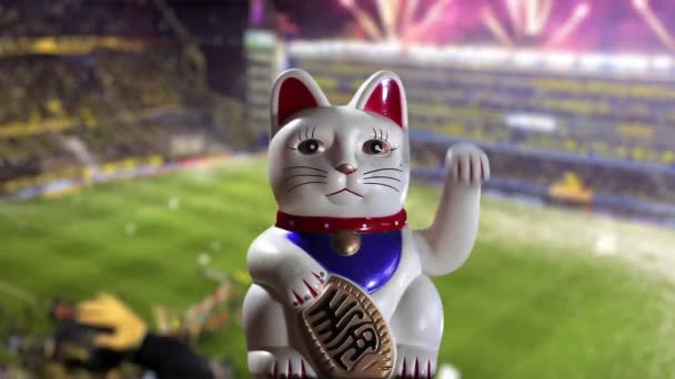 Maneki Neko猫或Beckoning猫对着模糊的足球场 — 图库视频影像