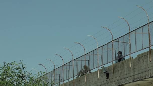 アルゼンチンのブエノスアイレス州の古い刑務所で警備フェンスと狭い歩道に沿って歩く刑務所の役員 — ストック動画