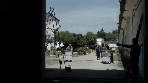 Ομάδα Κρατουμένων Που Σπρώχνουν Καρότσια Στην Αυλή Μιας Παλιάς Φυλακής — Αρχείο Βίντεο