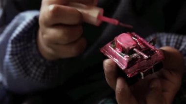 Tırnak cilasıyla Oyuncak Tankı Boyayan Genç Bir Kızın Elleri, Model Tanka Boya Uygulayan Kız. Yakın çekim. 4K Çözünürlüğü.