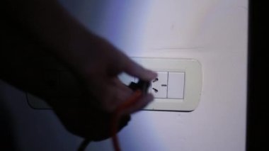 Elektrik kesintisi ya da elektrik kesintisi sırasında Karanlıktaki Apartman 'daki Duvara bir soket bağlarken Erkek El feneri kullanıyor. Yakın çekim. 4K Çözünürlüğü.
