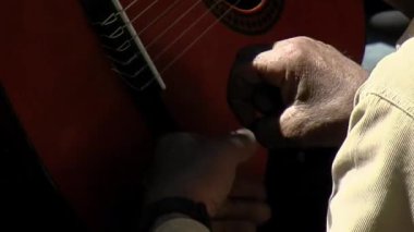 Neuquen, Patagonya, Arjantin 'de başka bir adam çalarken Yaşlı Bir Adam Gitarın Bedenine Vuruyor. Kapat..