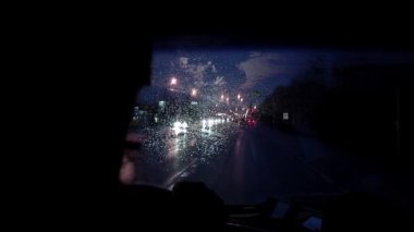 Silhouette of People Inside a Car on Road at Rainy Night. Close Up. 