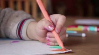 Masadaki kağıda resim çizen bir kızın eli, Evdeki Kağıt üzerinde renkli kalemle çizen küçük kız. Yakın çekim. 4K Çözünürlüğü.