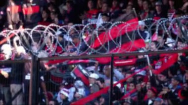 Güney Amerika, Arjantin 'deki bir futbol stadyumunda dikenli tellerin arkasındaki bulanık kalabalık. 4K Çözünürlüğü.