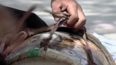 A Skilled Luthier Begins Restoration of 'Bombo Leguero' Drum, Removing Straps at his Workshop. Close Up.