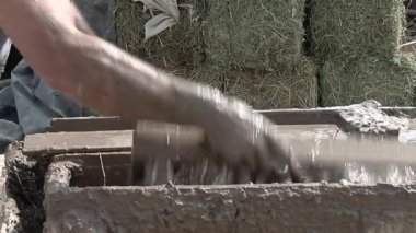 Yapı malzemesi olarak Adobe Tuğlaları Yapan Bir Adam, tipik olarak Dünya ve Organik Malzemeler 'den güneşte kurutulmuş tuğlalar yapıyor. Yakın plan.  