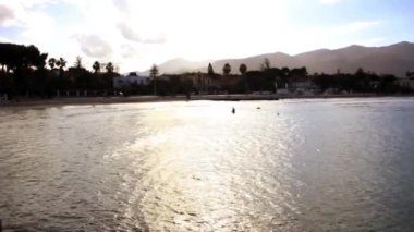 Günbatımı Huzuru: Sicilya, Mondello Sahili 'nin Sularında Yürüyen Bir Adamın Silüeti. 