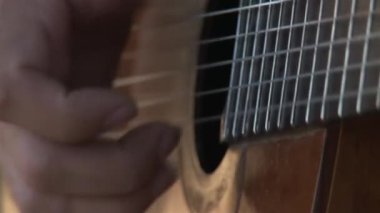 Adam klasik gitar çalıyor. Açık havada. Yakın plan.. 