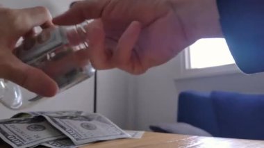 Evdeki cam kavanozdan 100 Dolarlık banknotları alan adam. Yakın çekim. 4K Çözünürlüğü.