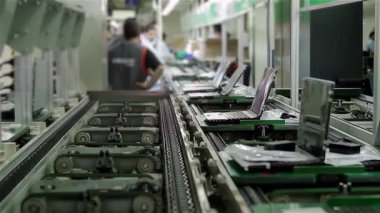 Bilgisayar montaj hattı, dizüstü bilgisayarlar bilgisayar fabrikasında taşınıyor, işçiler arka planda. 4K Çözünürlüğü.