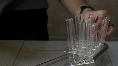 Lise öğrencisi kimya sınıfında test tüpleri düzenliyor. Yakın çekim. 4K Çözünürlüğü.