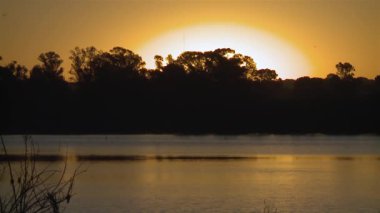Arjantin 'in La Pampa ilindeki Santa Rosa şehrinde gün batımı manzaralı Don Tomas Gölü.  