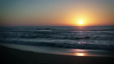 Atlantik kıyısında gün doğumunda, dalgalar kumsala çarpıyor. Zaman ayarlı. 4K Çözünürlüğü.