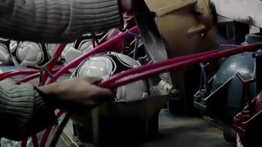 Futbol topu fabrikasında termoformasyon makinesinde top tutan bir işçi. Yaklaş - 4K