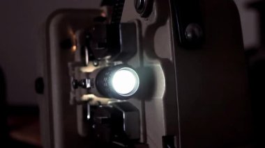 Sinemadaki karanlık bir projeksiyon kabininde operasyon yapan eski bir film projektörü. Yakın çekim. 4K Çözünürlüğü.