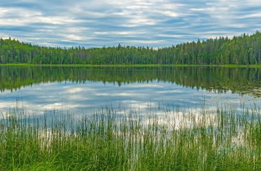 Sabah Bulutları Manitoba 'daki Duck Mountain İl Parkı' nda Sprey Gölü 'nde yemyeşil bir gölde.