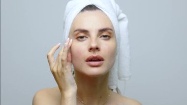 Güzel genç bir kadın aynanın önünde cildine bakıyor, yüzünü kontrol ediyor. Güzellik, cilt bakımı. Beyaz arkaplanda