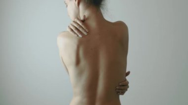 Çok güzel genç bir kadın nazikçe kendi vücudunu okşuyor. Beyaz arkaplanda