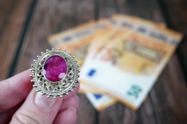 手拿着红宝石戒指和欧元作为背景 典当行的概念 — 图库照片