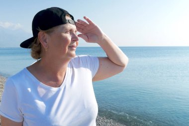 Deniz sahilinde sırt çantalı, maceraperest bir kadın. Emekliler için yaz turizmi. Açık havada.