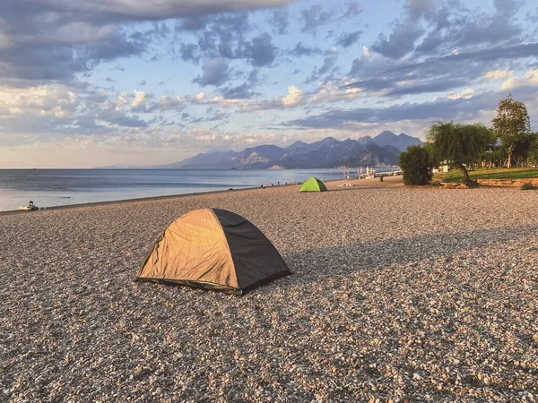 Family camping on the sea beach and mountains in the background, camping tent near the sea, independent tourism concept