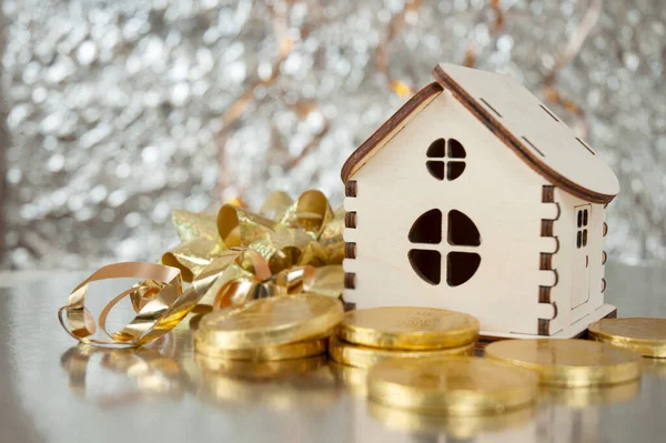 wooden house model, gold chocolate coins and new year decorations on shining background with copy space, xmas background, Wealth concept. New year sales for new houses concept