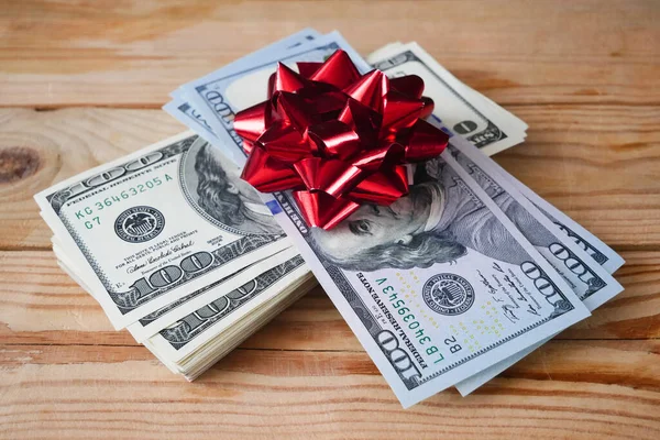 Money gift, big stack of money with red bow on wooden background, concept