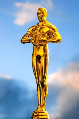 Golden man statue on blue sky background, closeup