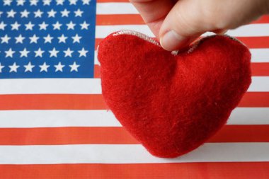 National american flag and heart symbol in hand. american heart month in February, closeup