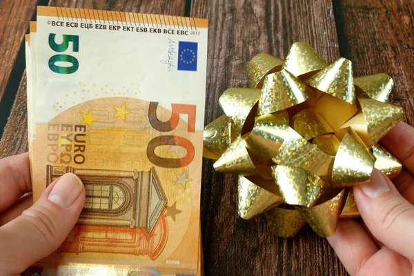 Money gift, big stack of money with golden bow on wooden background, concept