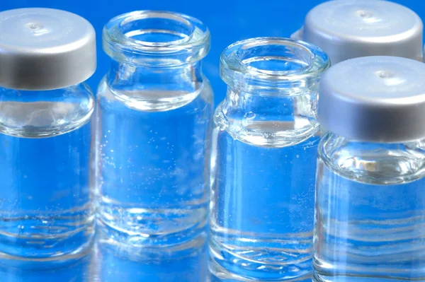 bottles of vaccine on blue background, production medicine vaccine, closeup