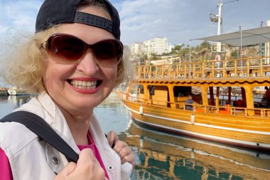 Senior adventureisageless woman with backpack on the sea beach. Summer active tourism for pensioner. Turkey, Antalya, Outdoors