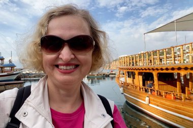 Senior adventureisageless woman with backpack on the sea beach. Summer active tourism for pensioner. Turkey, Antalya, Outdoors