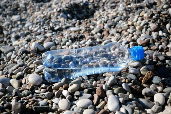 Plastic water bottles pollution in sea beach, dirty coast, beach pollution, closeup