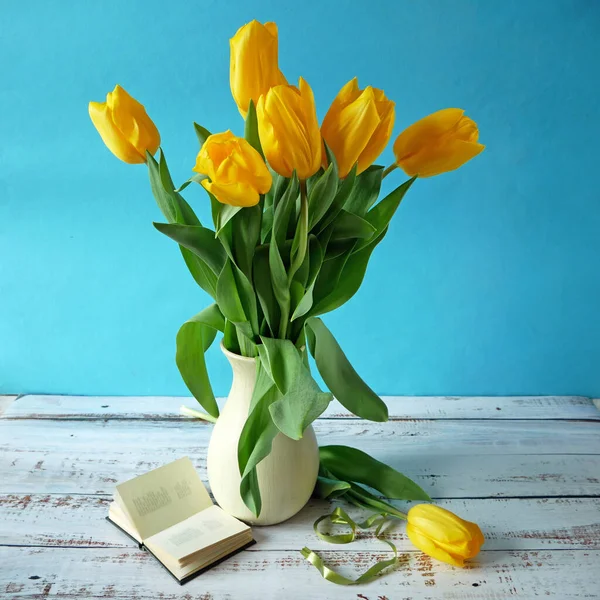 Still life with yellow tulips bunch, book on artistic background. World Teacher\'s Day concept