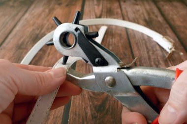 Bronzlaştırıcı ile deri kemer üretme süreci. Yumruk atarak kayış deliklerini deldim. Kemerli Delik Yumruklayıcı Güç Desteği Ağır Görevli Dönen Gözlü Yumruk Kerpeteni. Yakın çekim.