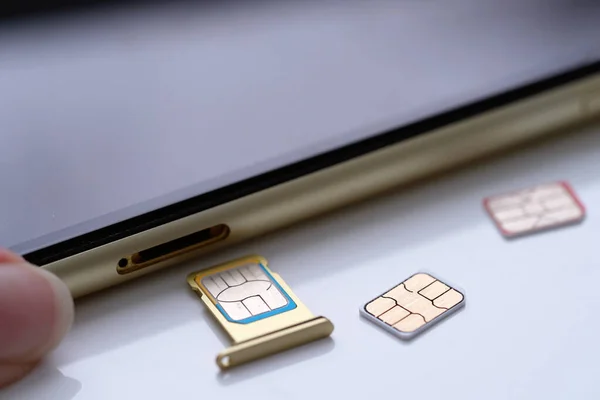 Person inserting a sim card into back of mobile phone, Sim card in tray being inserted into phone, closeup