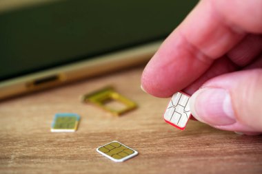 Person inserting a sim card into back of mobile phone, Sim card in tray being inserted into phone, closeup
