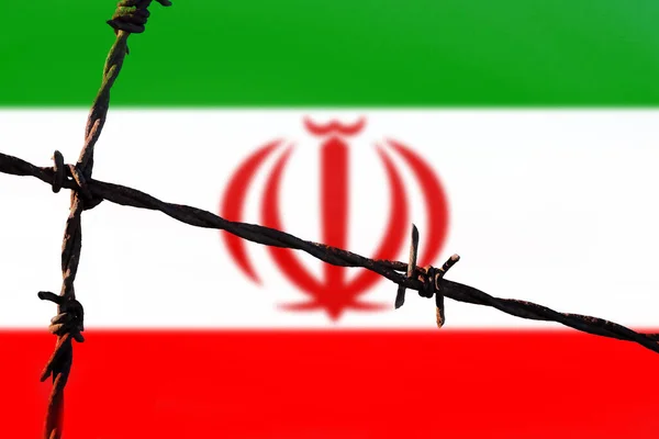 Iran flag behind barbed wire fence. Concept of sanctions, embargo, dictatorship, discrimination and violation of human rights and freedom in Iran. Closeup