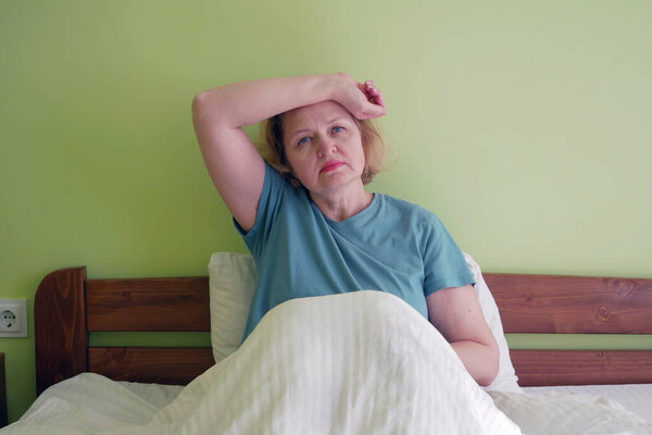 Middle aged blond hair woman with head ache in bed, indoors