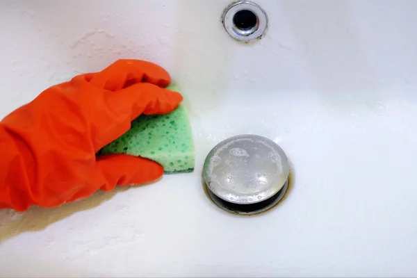 woman cleaning a bathroom\'s sink with sponge, Person cleaning the kitchen sink with a glove, closeup