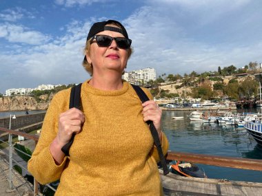 Son sınıf macerası, sırt çantalı ve eski Antalya Hindi 'sinde yürüyen yaşsız bir kadın. Emekliler için yaz turizmi. Açık havada.