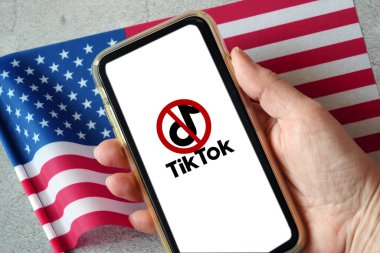 Lviv, Ukrayna - 04 04 04 2023: Akıllı telefona TikTok yasağı. Akıllı telefon ekranında TikTok uygulaması logosu ve arka planda ABD bayrakları.
