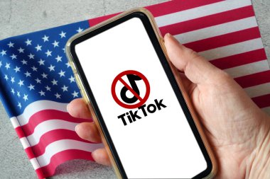 Lviv, Ukraine - 04 04 2023: TikTok ban on smartphone.  TikTok app logo on a smartphone screen and flags of United States on the background. clipart